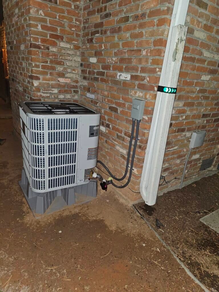 An outdoor condenser unit installed against a brick wall by UniColorado
