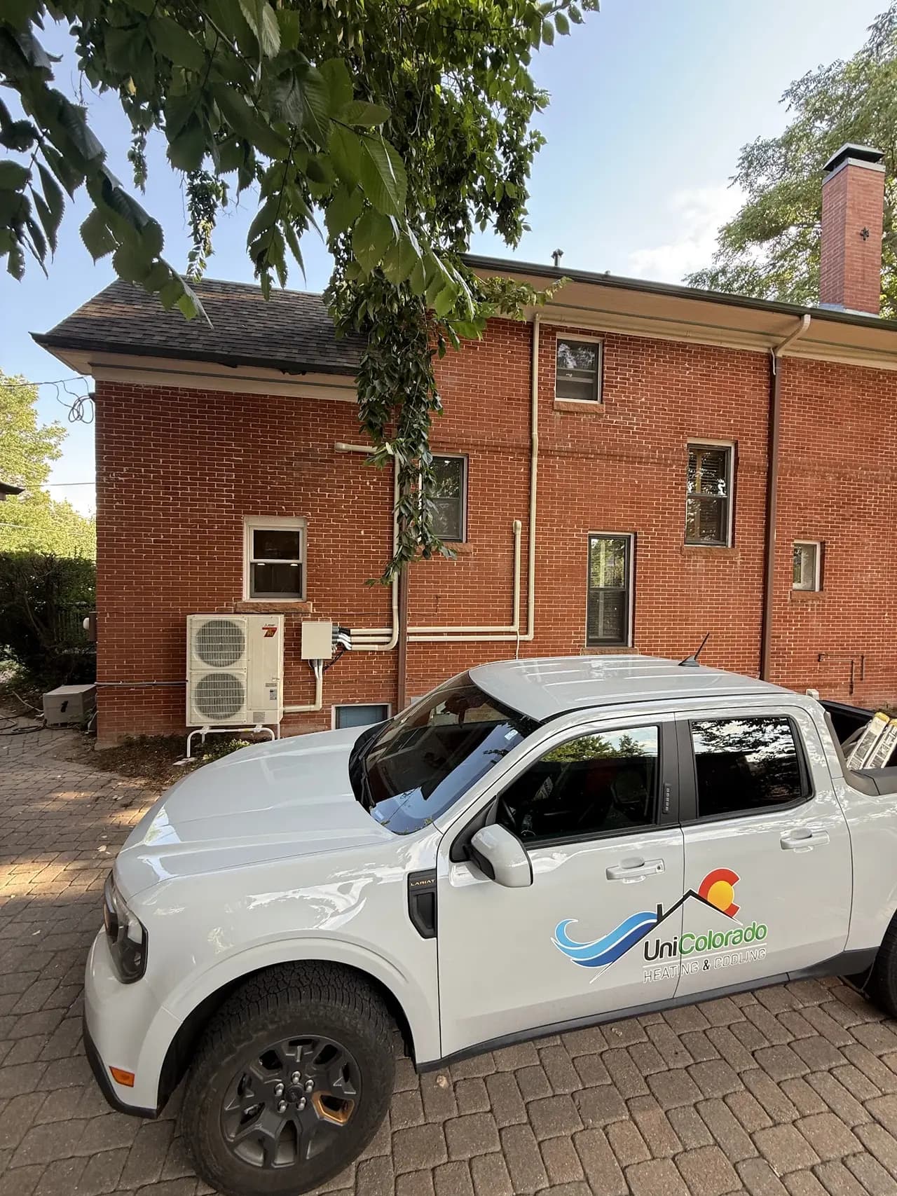 UniColorado truck at a heat pump installation job site with outdoor condenser unit