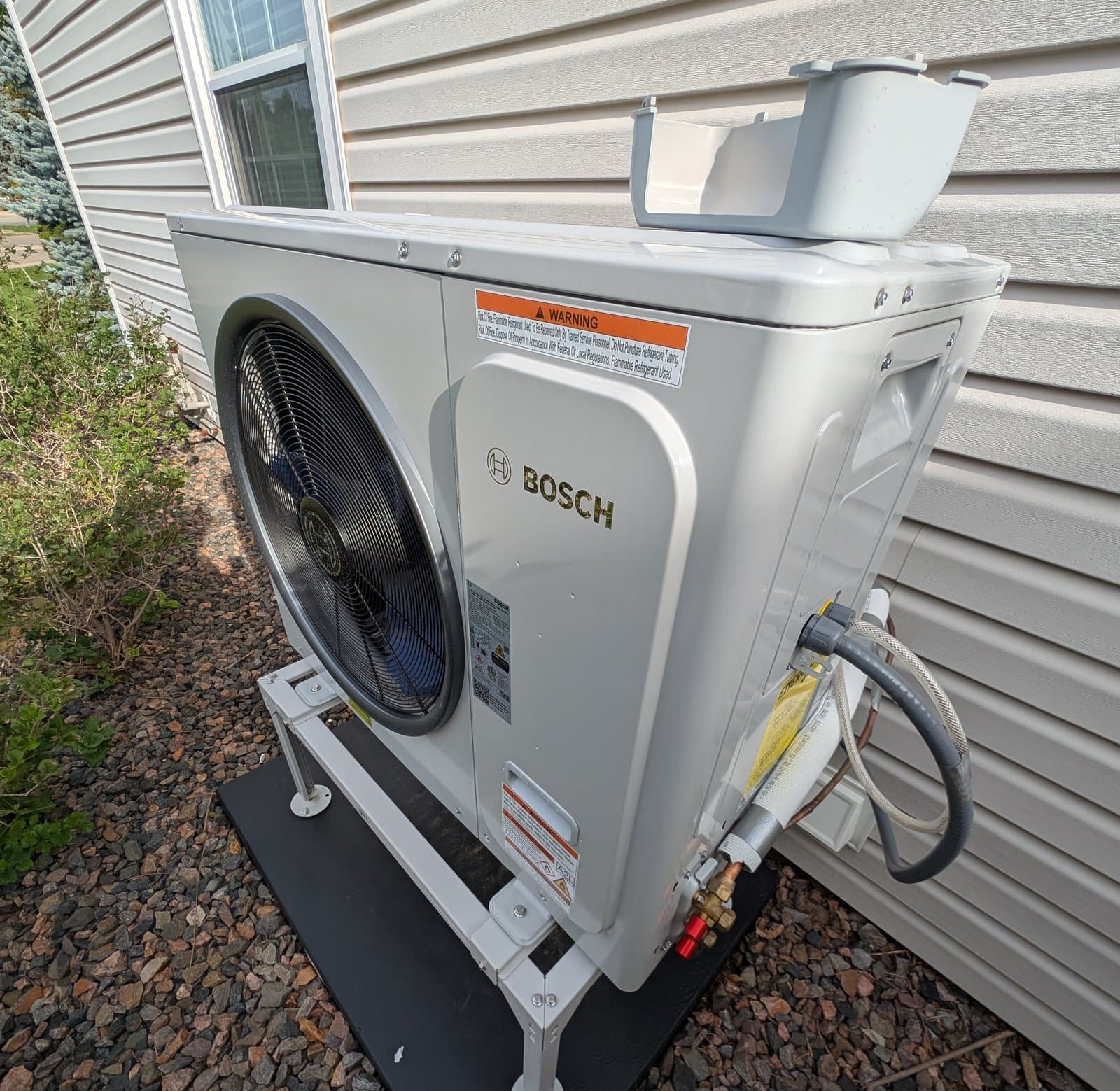 Bosch IDS heat pump outdoor unit on a stand and pad beside a Denver home, installed September 2026 on R-454B