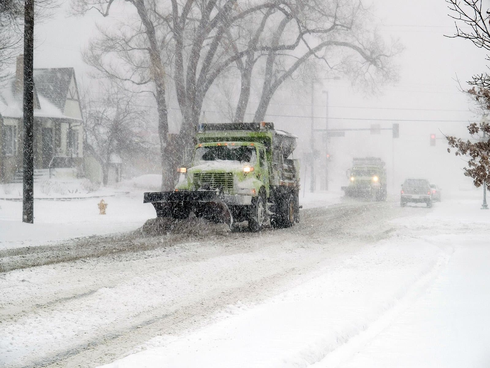 Snowplows clearing a Denver residential street during a heavy upslope blizzard