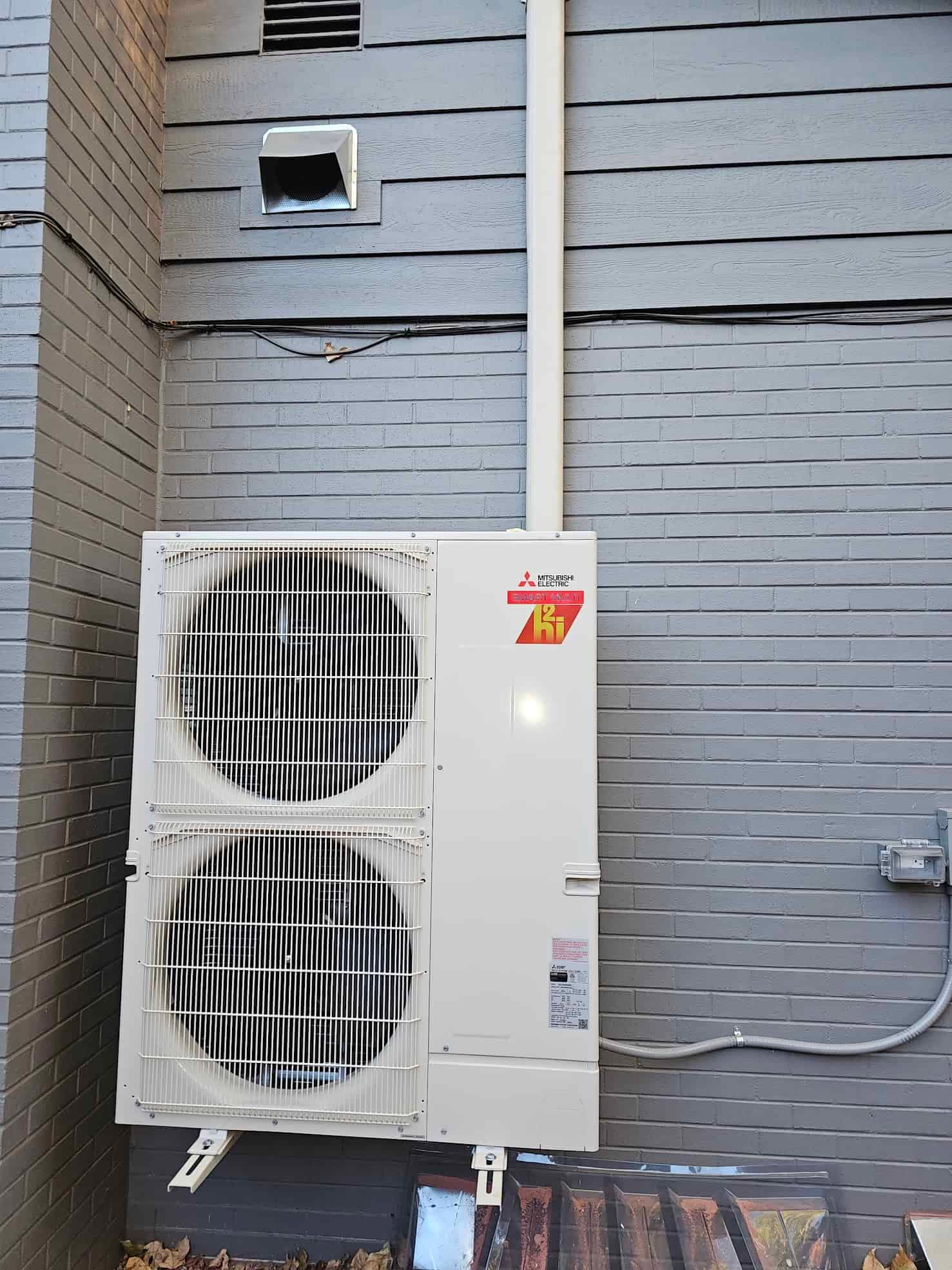Mitsubishi outdoor condenser unit installed beside a brick wall