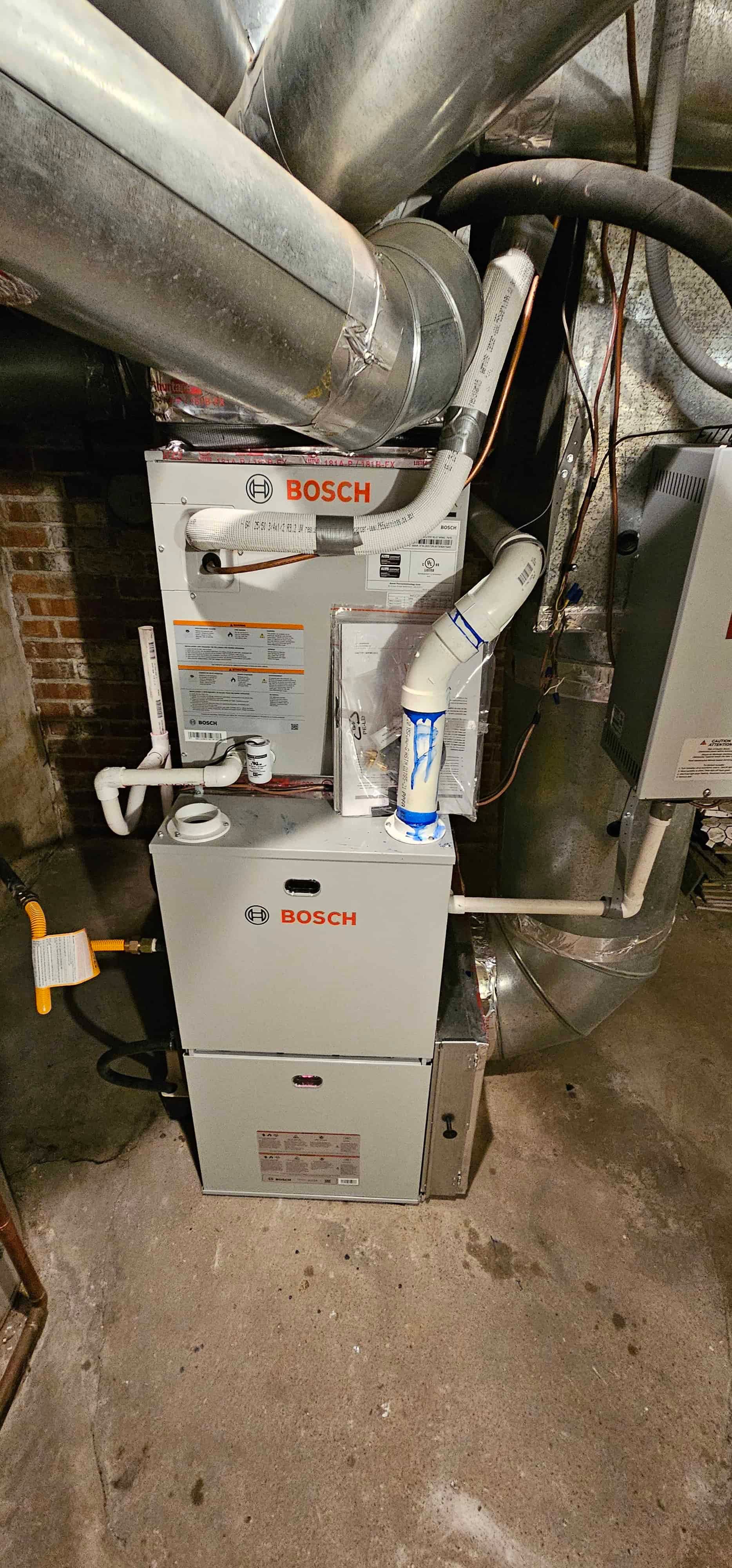 Bosch furnace and air handler in mechanical room with brick wall