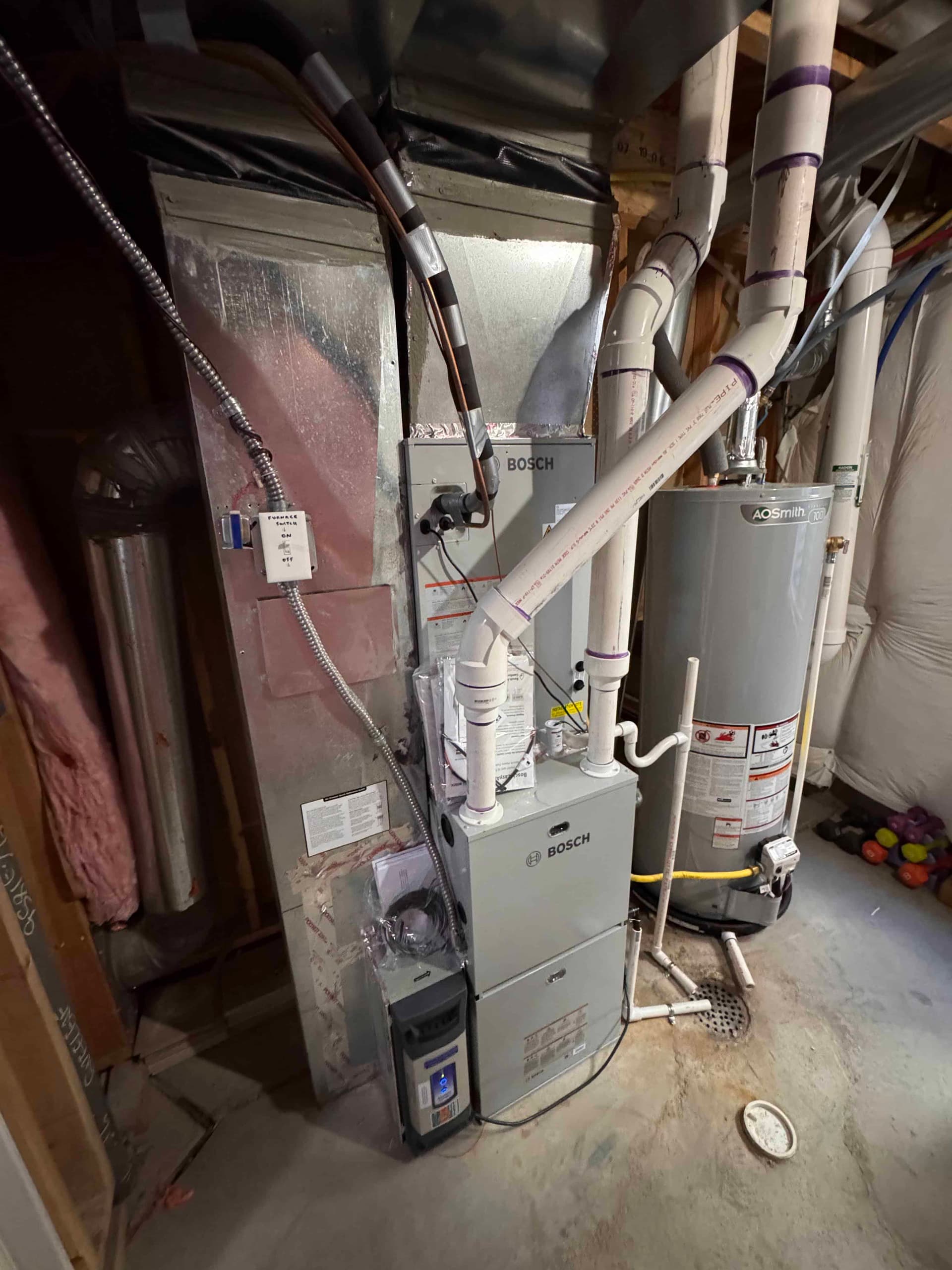 Bosch furnace with AO Smith water heater and pink insulation in basement