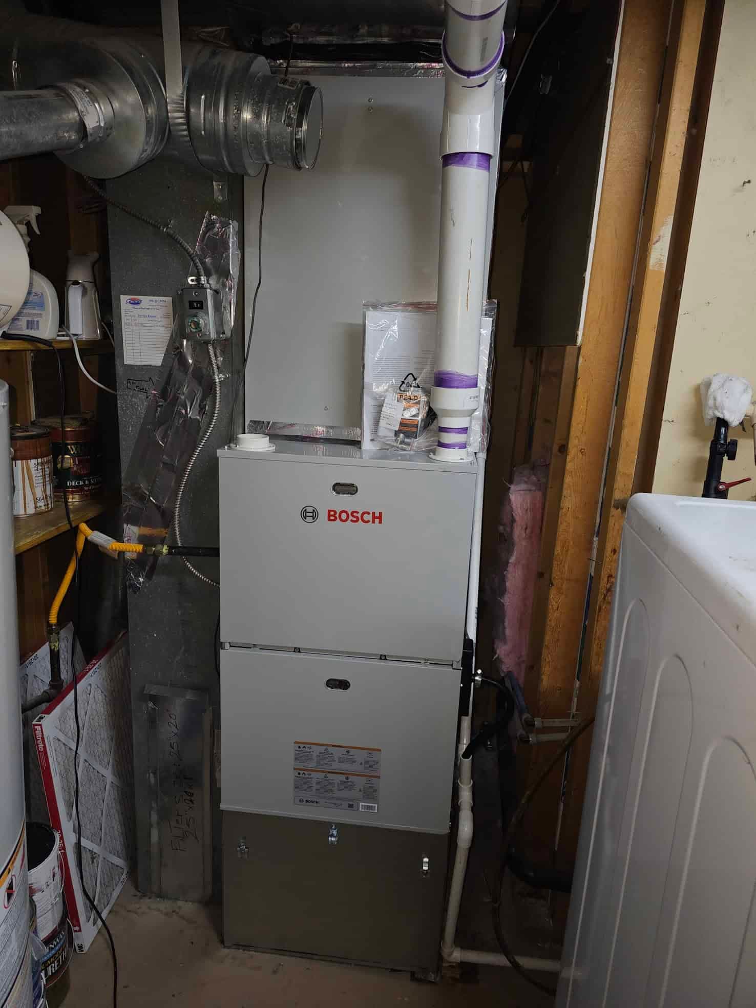 Bosch furnace in basement utility room with purple taped pipes