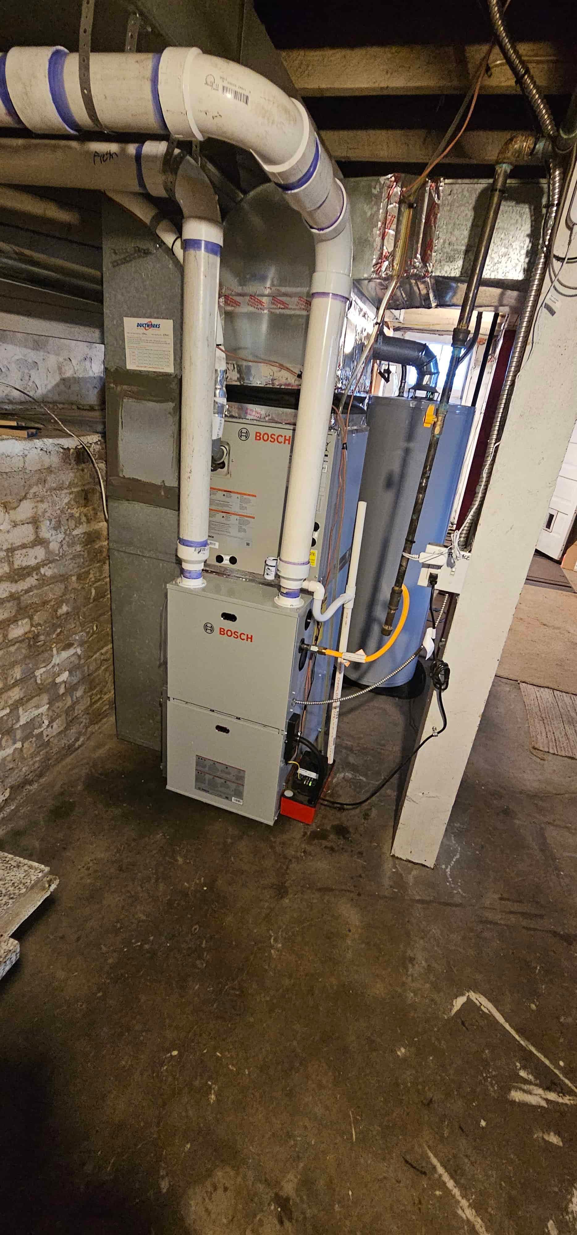 Bosch furnace with blue tape on pipes in basement utility room