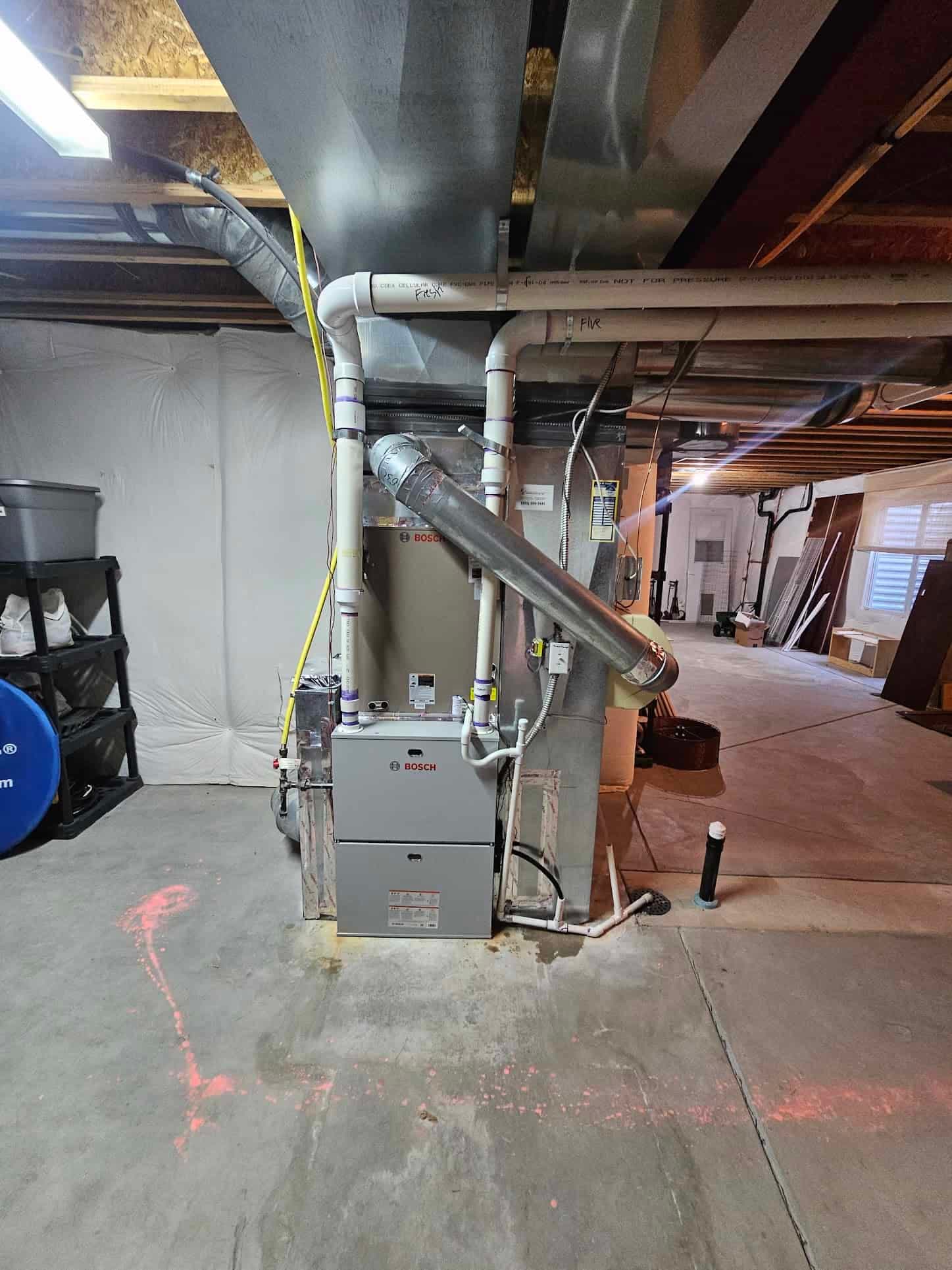 Bosch furnace installation in basement with concrete ceiling and yellow label