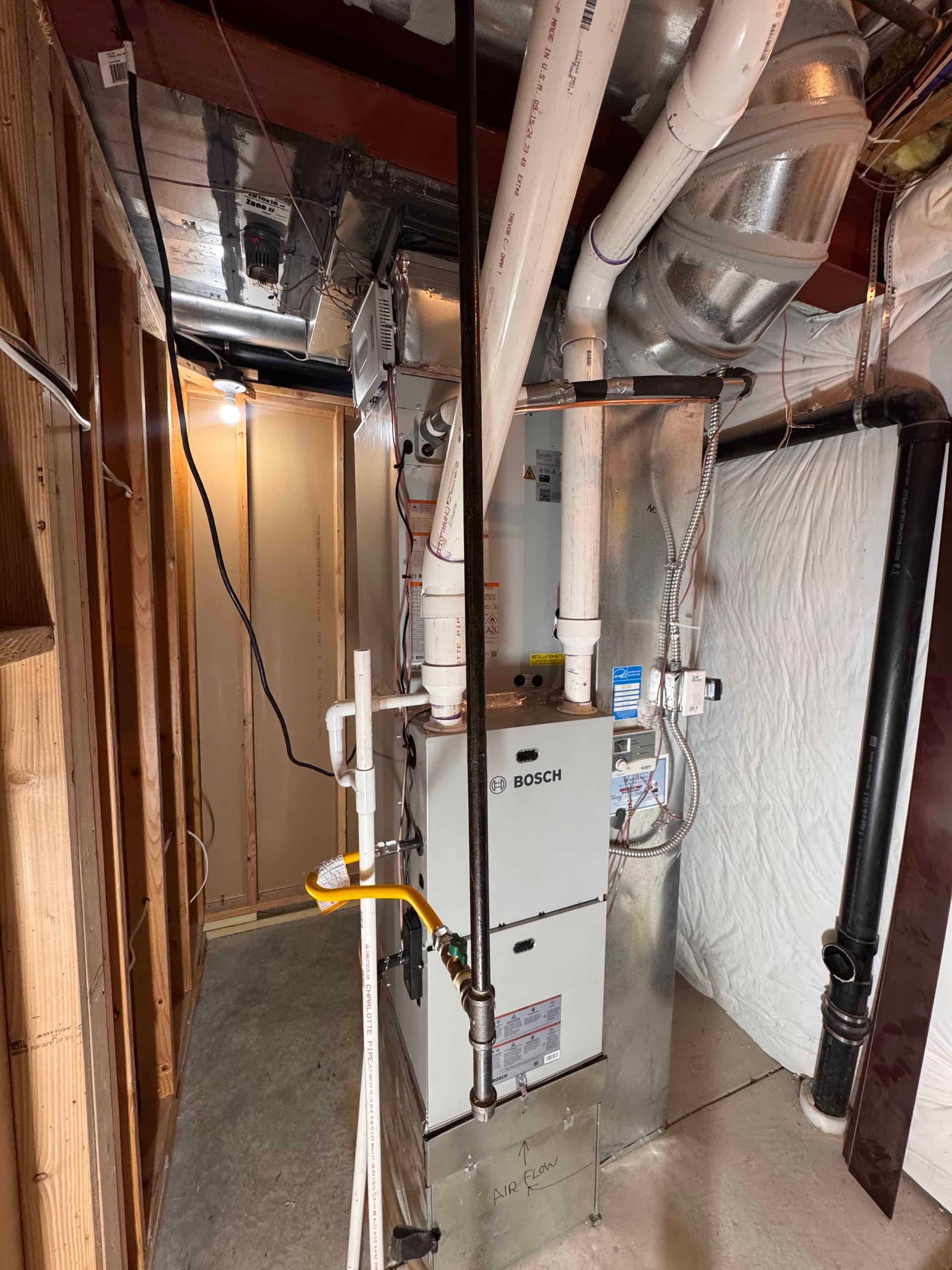 Bosch furnace installation in unfinished basement with yellow label