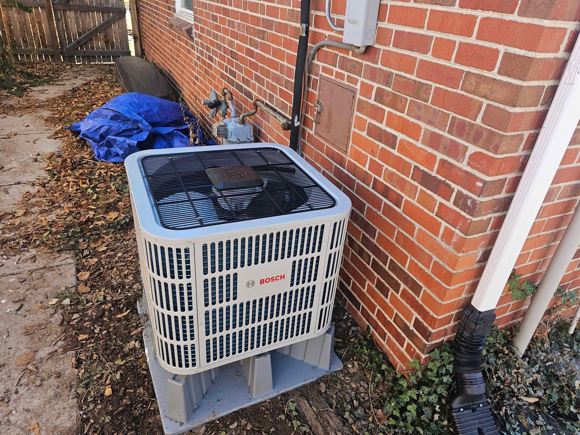 Outdoor AC condenser with weathering and debris around the base