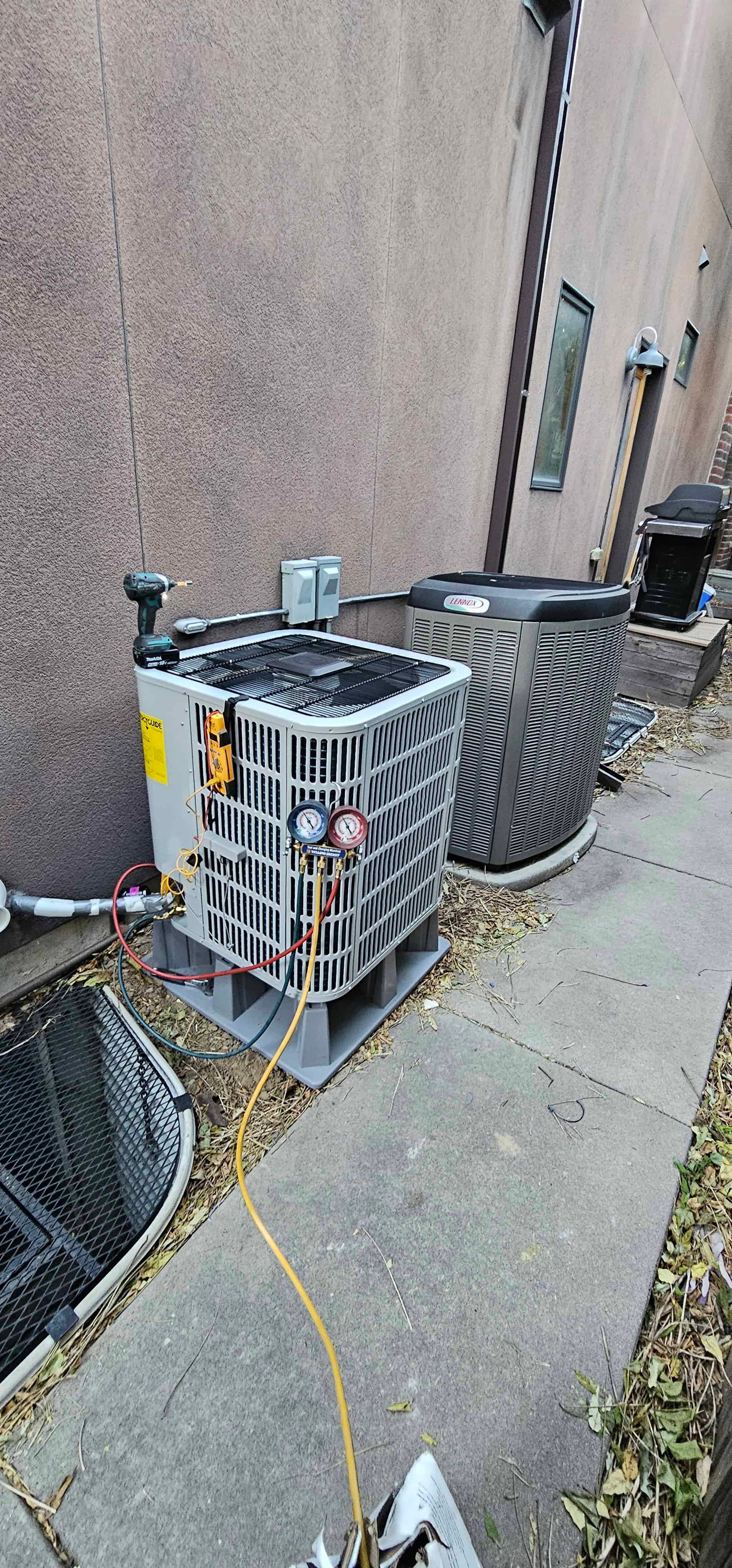 Refrigerant gauges connected to outdoor AC condenser unit during diagnostic testing