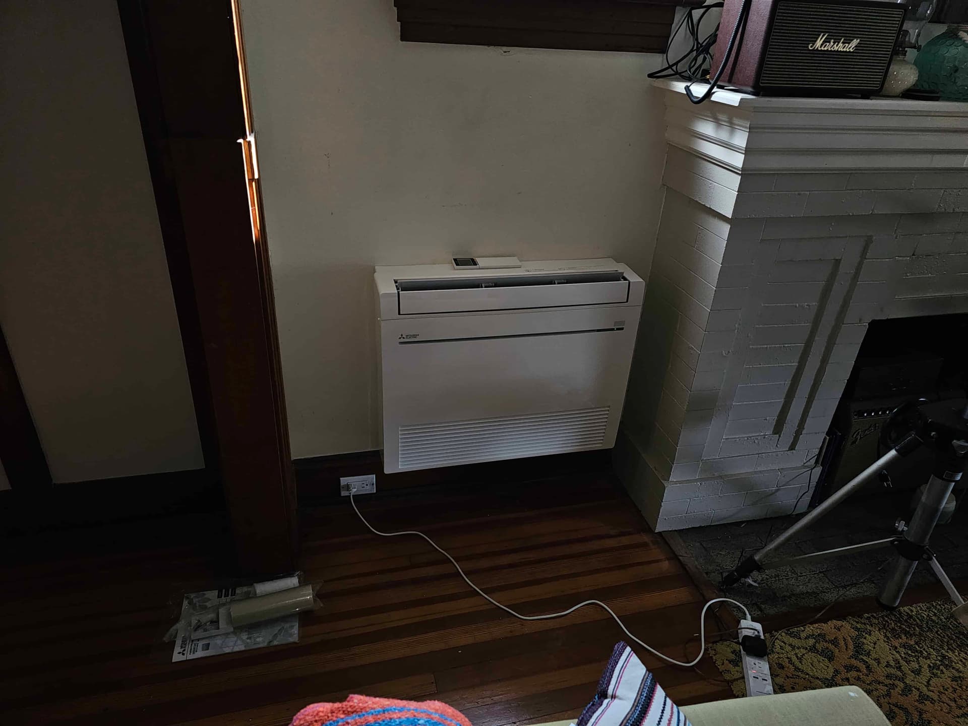 Mitsubishi mini-split indoor unit in a living room with white brick wall
